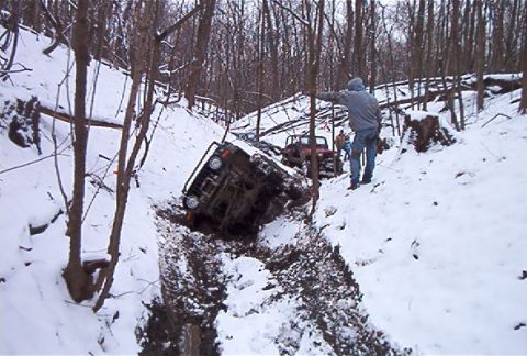 1992 Ford Bronco - Off-road vehicles struggle in a deep, snow-covered ravine with a person observing the scene.