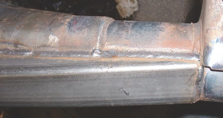 Close-up of welded metal frame sections with visible weld beads and some rust