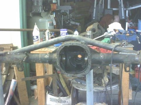1995 Ford Bronco - A disassembled rear axle assembly is shown in a cluttered workshop environment.
