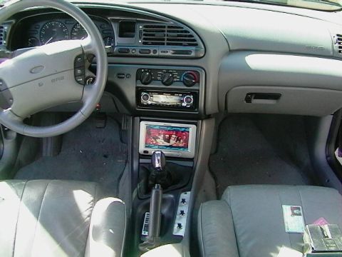 1995 Ford Contour - Interior view of a car's dashboard, center console, and seats, showing aftermarket audio equipment.