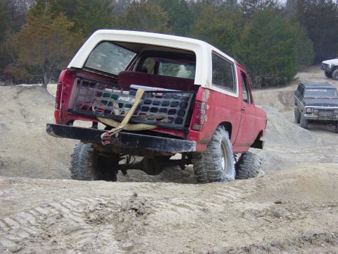 1983 Ford Bronco - This red SUV is navigating a dirt track with another vehicle in the background.