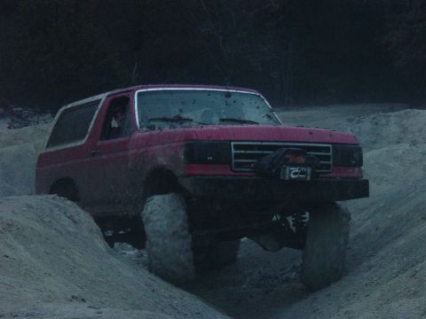 1983 Ford Bronco - Red Ford Bronco navigating a challenging off-road terrain.