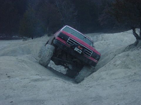 1983 Ford Bronco - This truck is navigating a steep, sandy incline with large, aggressive tires.