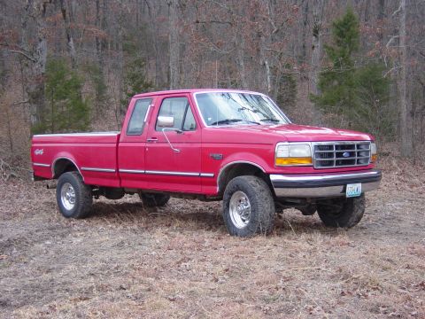 1983 Ford Bronco - This red Ford F-250 pickup truck is parked in a wooded area.