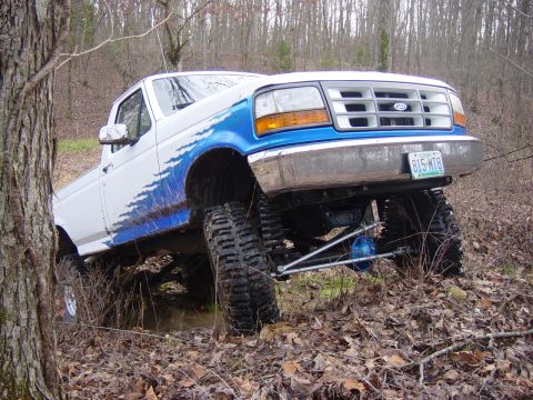 1983 Ford Bronco - This lifted 1995 Ford F-150 with custom blue graphics navigates a muddy, wooded trail.