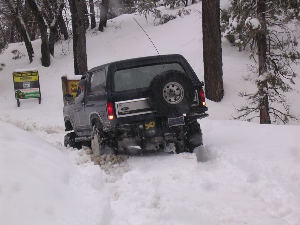 Ford Bronco driving through deep snow, spare tire mounted on the back