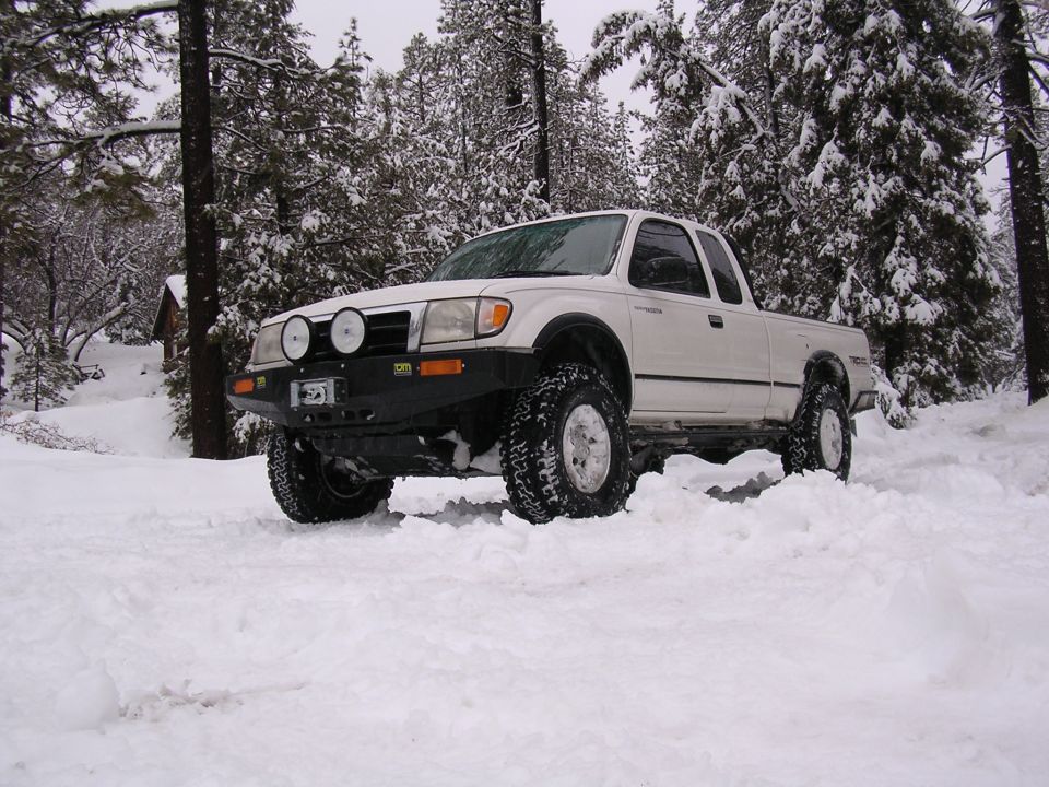 White 1999 Toyota Tacoma in snow with aftermarket bumper and off-road tires