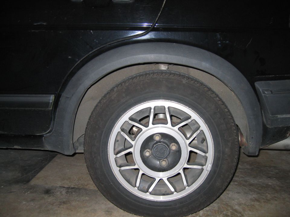 Black car rear wheel with multi-spoke alloy and worn tire close-up