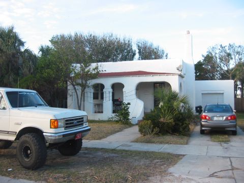 1989 Ford Bronco - A white pickup truck with off-road tires is parked in front of a house, with another car in the driveway.