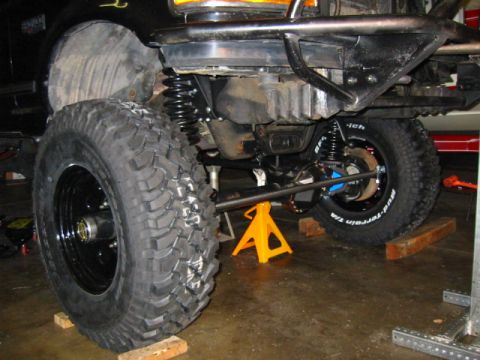 1992 Ford Bronco - Close-up view of a modified off-road vehicle's suspension system, supported by jack stands.