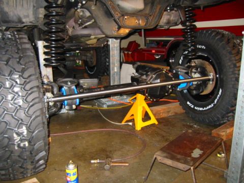 1992 Ford Bronco - Vehicle undercarriage with suspension and drivetrain components visible, undergoing maintenance.