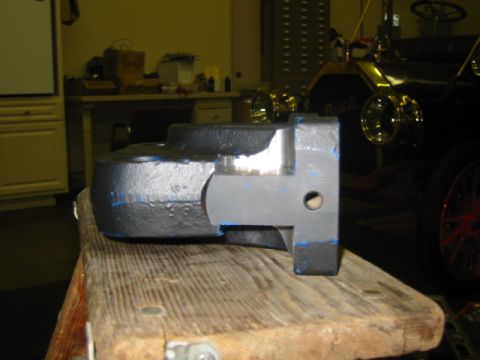 1992 Ford Bronco - A close-up view of a metal component rests on a wooden surface, with a vintage automobile visible in the background.