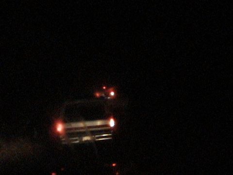 1991 Ford Bronco - Dark, blurry night shot of a truck or SUV facing the camera with its headlights and amber marker lights lit and a roll bar or light bar vis…