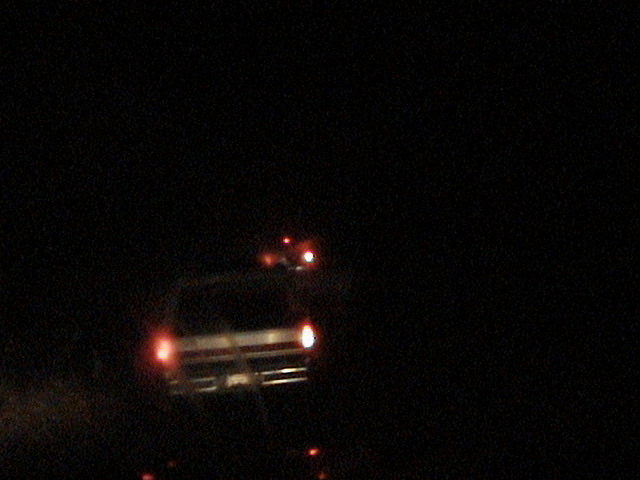 Blurry night photo of a truck with headlights and marker lights on