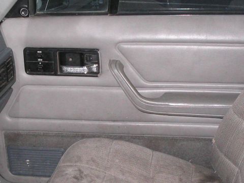 1991 Ford Bronco - Close-up of a vehicle's interior door panel, showing the handle, lock controls, and part of the seat.