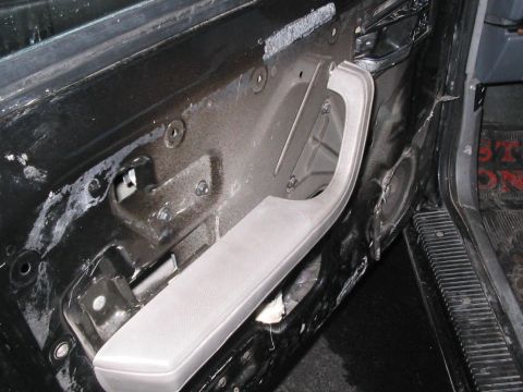 1991 Ford Bronco - Interior view of a car door with the panel removed, revealing the inner workings and a gray armrest.