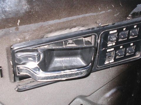 1991 Ford Bronco - Close-up of interior door handle and power window controls, showing various lock and window switches.