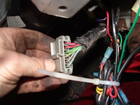 1990 Ford Bronco - Close-up of a gray wiring harness connector with various colored wires being held.