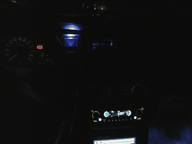 Car interior at night showing dashboard gauges and a car stereo display