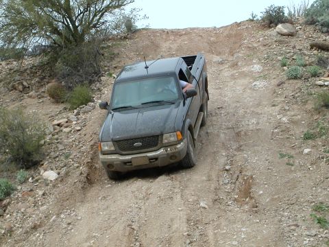 1993 Ford Bronco - A dark gray Ford Ranger navigates a steep, dusty off-road trail.
