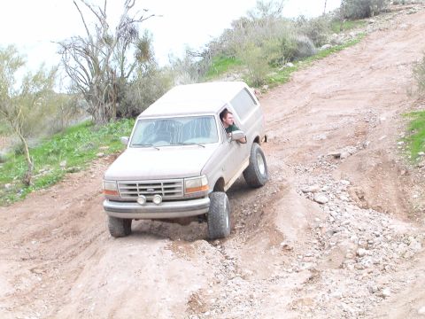 1993 Ford Bronco - A 1993 Ford Bronco navigates a steep, rocky incline on a dirt trail.