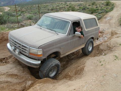 1993 Ford Bronco - This Ford Bronco is shown navigating a challenging off-road trail with steep inclines and deep ruts.