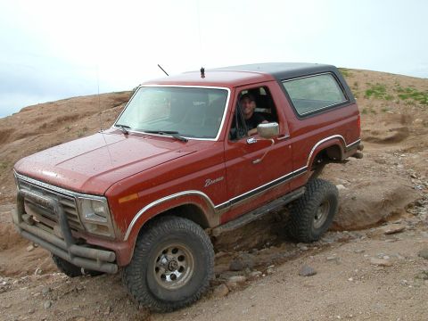 1993 Ford Bronco - This red Ford Bronco with a black top navigates a rocky off-road trail.