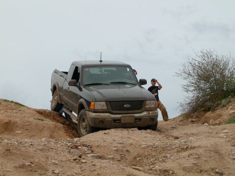 1993 Ford Bronco - Ford Ranger pickup truck is shown off-roading on a dirt trail.