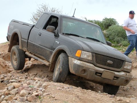1993 Ford Bronco - This Ford Ranger is navigating a rocky off-road path, with a person walking in the background.