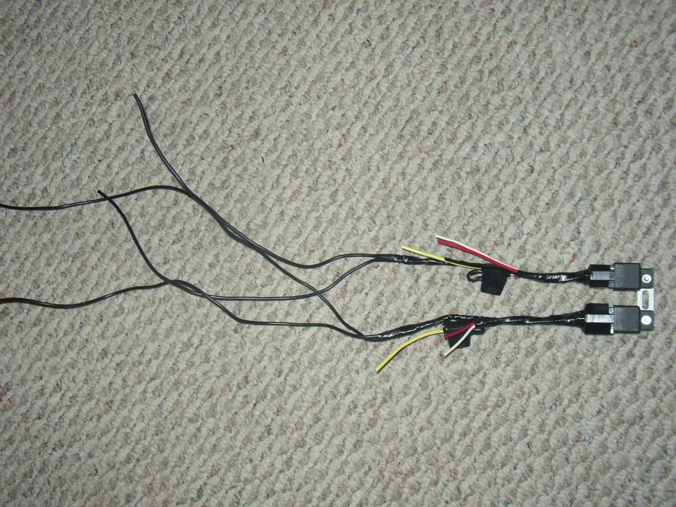 Pair of wiring harnesses with relays and connectors laid on tan carpet