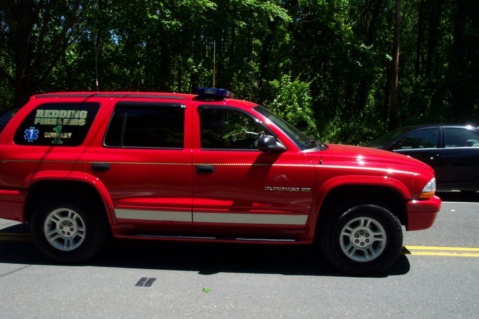 Red Dodge Durango fire/EMS SUV with roof light and Redding Fire & EMS Company 1 decal, side view on a road