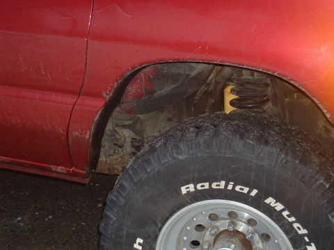 1994 Ford E350 - Rear wheel well and suspension detail on a red vehicle. Tire reads 'Radial M/T'.