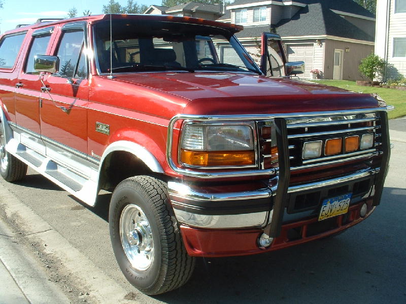 Red crew-cab truck with chrome grille guard, front 3/4 view in driveway