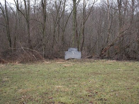 1993 Ford Probe - A concrete barrier sits in a wooded area, surrounded by bare trees and dry brush.