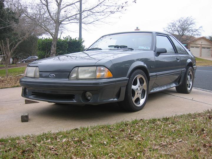 Gray Fox-body Ford Mustang GT hatchback with 5.0 badge parked on a lawn