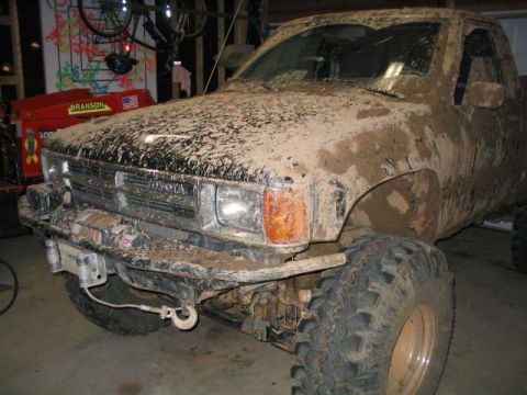 1986 Ford F-150 - This mud-caked Toyota truck is shown from the front three-quarter angle, with its grille and headlights partially obscured by dirt.