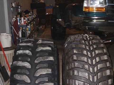 1996 Ford Bronco - Comparison of two aggressive off-road tires, with a green truck in the background.