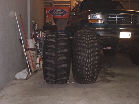1996 Ford Bronco - Green Ford truck with large tires in a garage, showing the front grille and headlights.