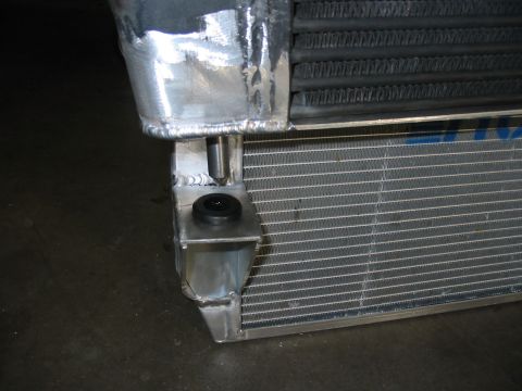 1993 Ford Taurus - Custom aluminum radiator part with a black rubber isolator and mounting bracket, showing Supermotors.net branding.