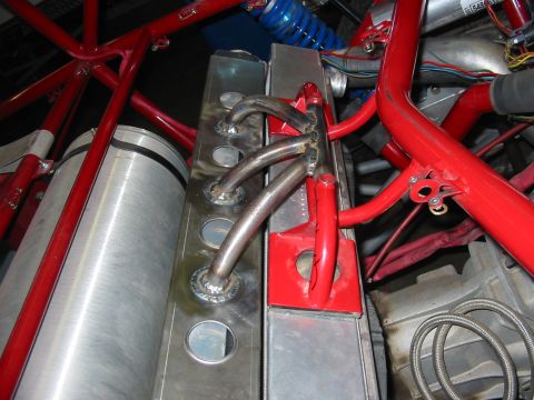 1993 Ford Taurus - Custom exhaust manifold pipes are welded to a radiator assembly, surrounded by red roll cage tubing.