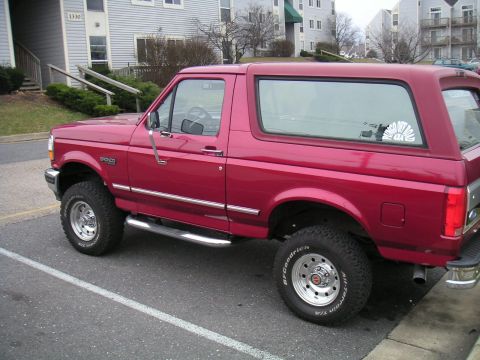 1994 Ford Bronco - This red 1994 Ford Bronco is parked in front of an apartment building.