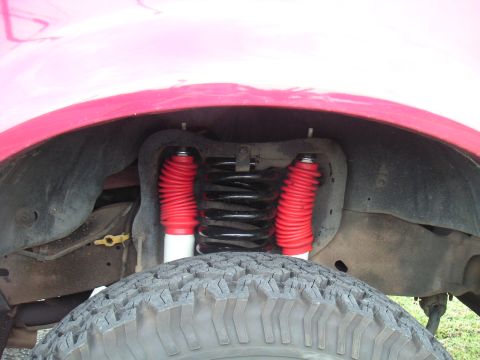 1994 Ford Bronco - Close-up view of the suspension system, red shock absorbers and a coil spring.