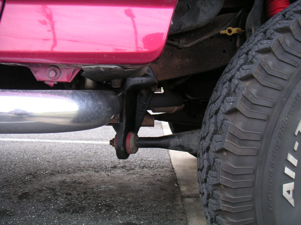 Close-up of a vehicle's rear suspension, showing the exhaust pipe, shock absorber, and tire