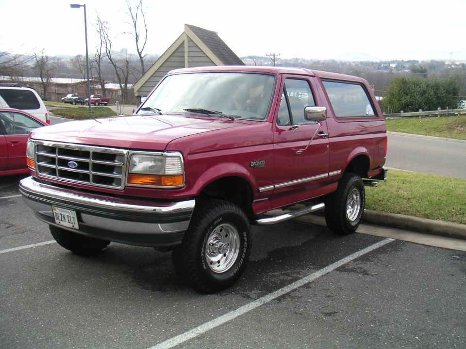 Red 1994 Ford Bronco with lift kit parked in a lot
