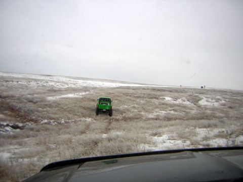1995 Ford Bronco - A lone green vehicle navigates a desolate, snow-dusted landscape.