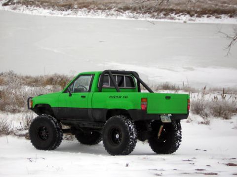 1995 Ford Bronco - A heavily modified green pickup truck with oversized tires sits in a snowy landscape.