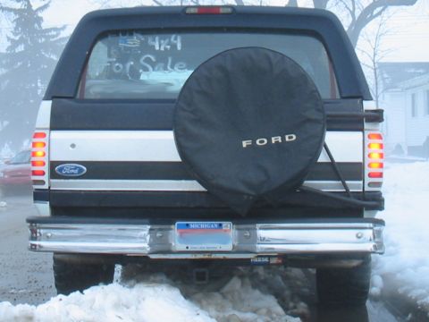 1992 Ford Bronco - The rear of a 1992 Ford Bronco is visible, with a spare tire cover and 'For Sale' sign in the window.
