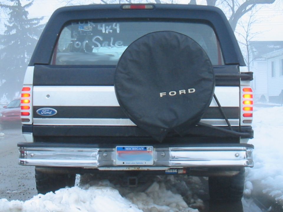 Rear view of a 1992 Ford Bronco with a black spare tire cover and a Michigan license plate