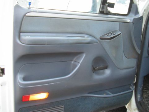 1992 Ford Bronco - The interior door panel of a vehicle shows the window controls, door handle, and a small amber light.