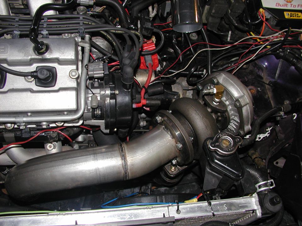 Engine bay with turbocharger, welded stainless downpipe, distributor and wiring in a 1996 Ford Probe